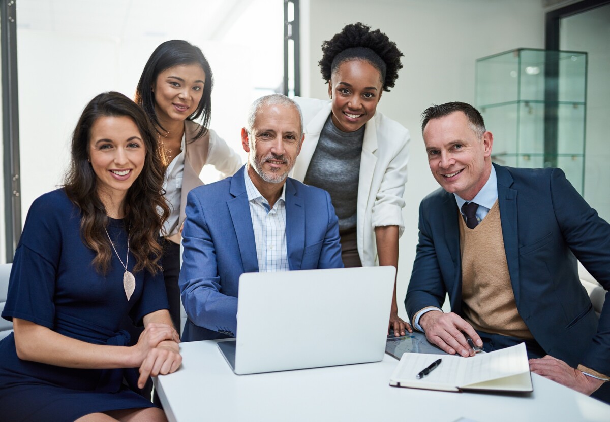 Portrait of a group of businesspeople working together on a laptop in a modern office
